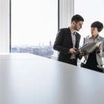 Businesspeople standing in office looking at paperwork